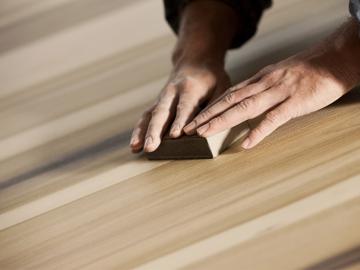 A carpenter sanding a wood surface.