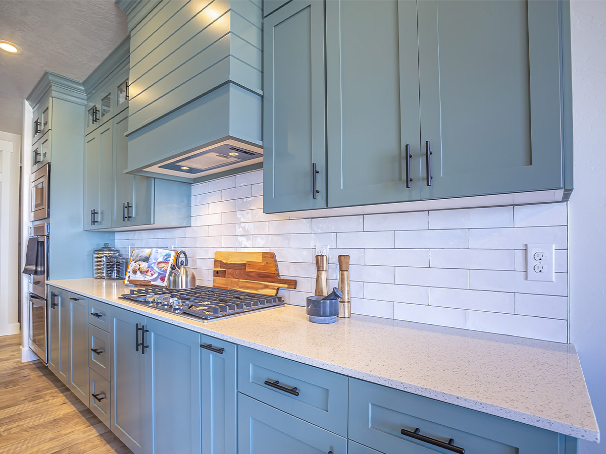 A kitchen with bluish grey cabinets.