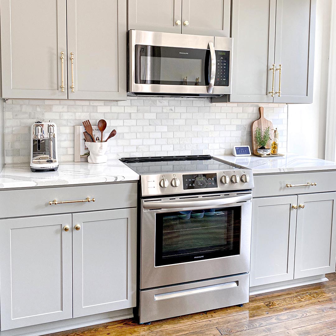 kitchen with light gray cabinets that have gold hardware